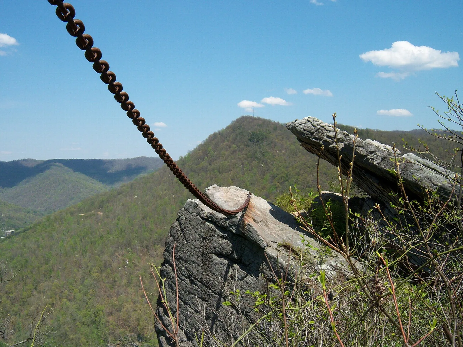 Large chain running to a split rock outcrop on a ridge above green mountains