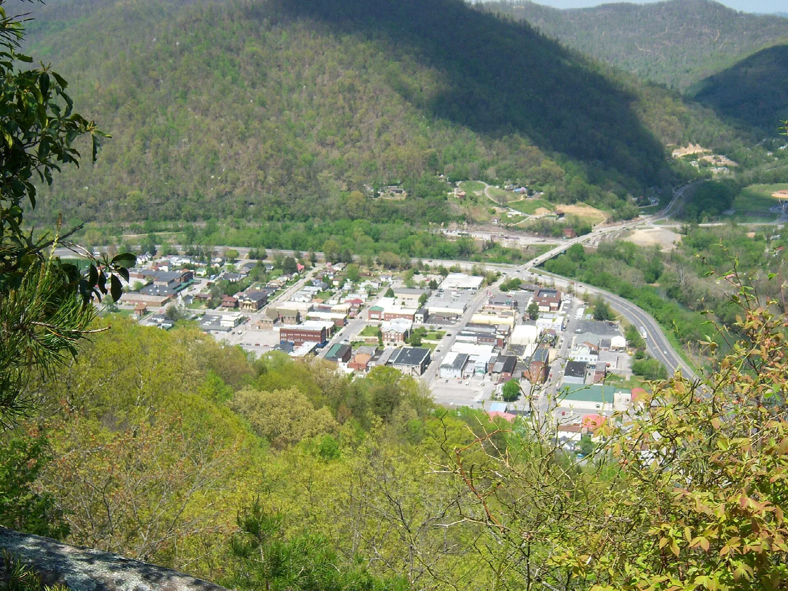 Town in a mountain valley seen from above through spring trees