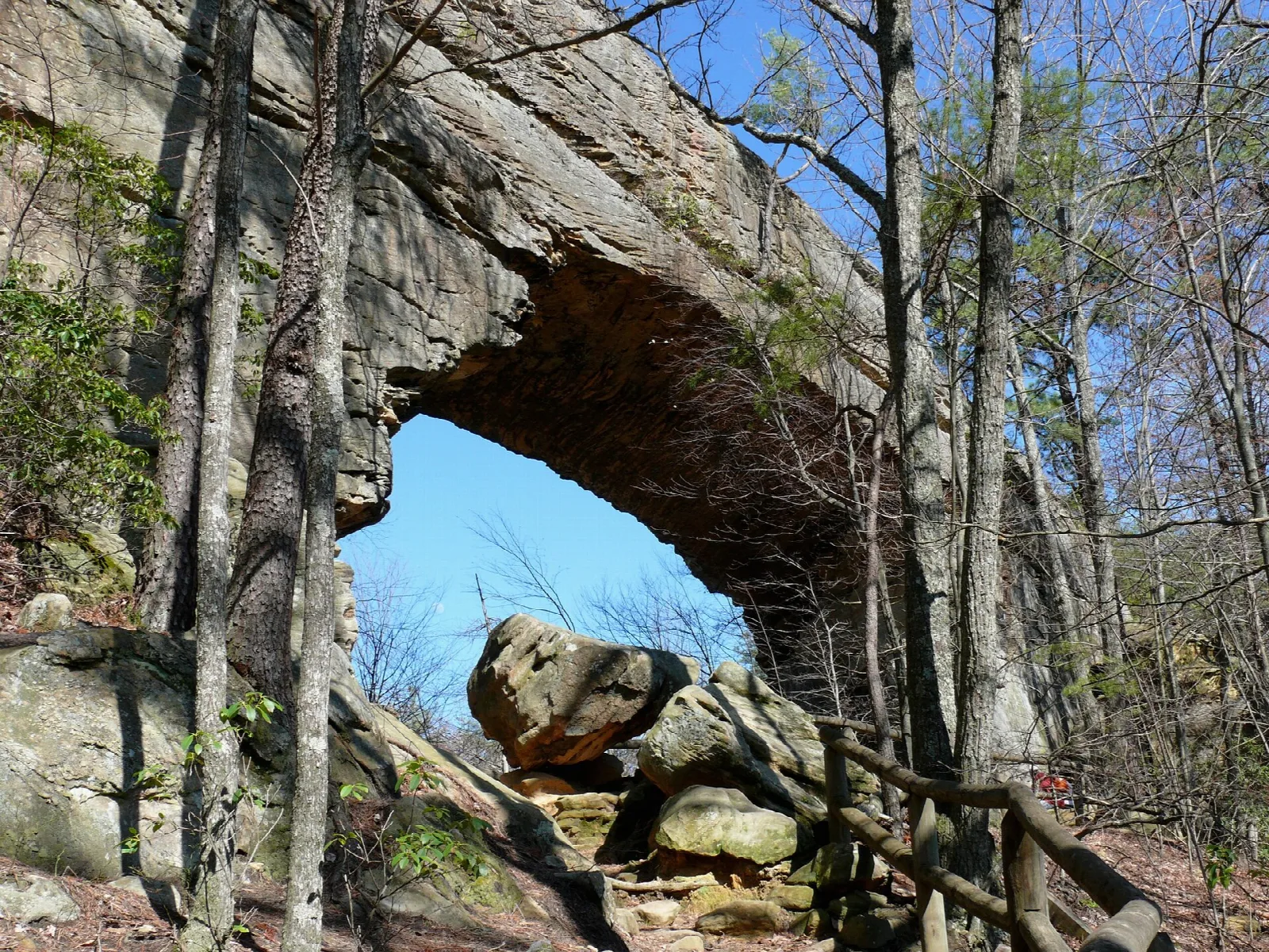 Sandstone arch with a patch of blue sky showing through, framed by bare trees