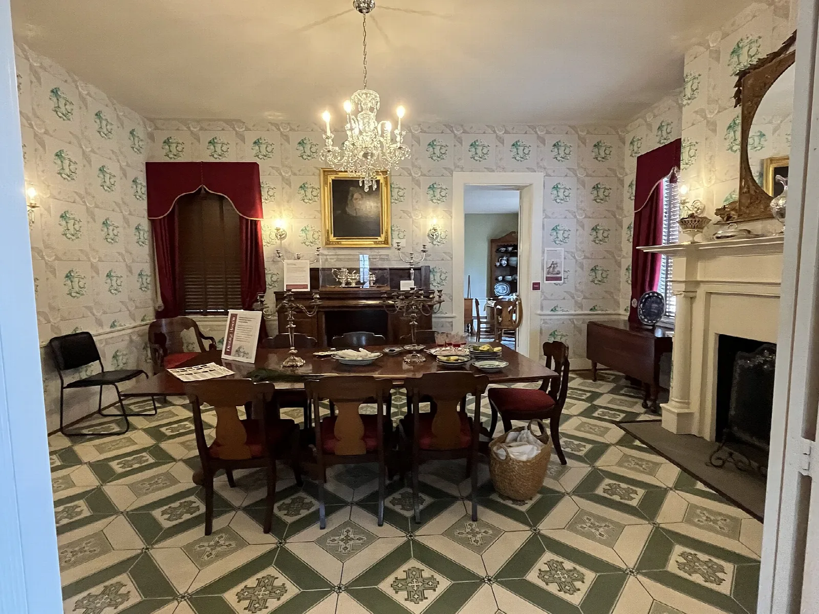 Room with a long wooden table, chandelier and green patterned tile floor