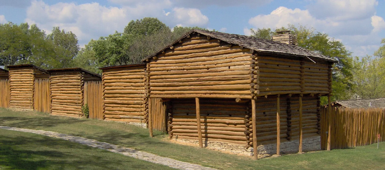 Log blockhouses and cabins of the reconstructed fort on a grassy lawn