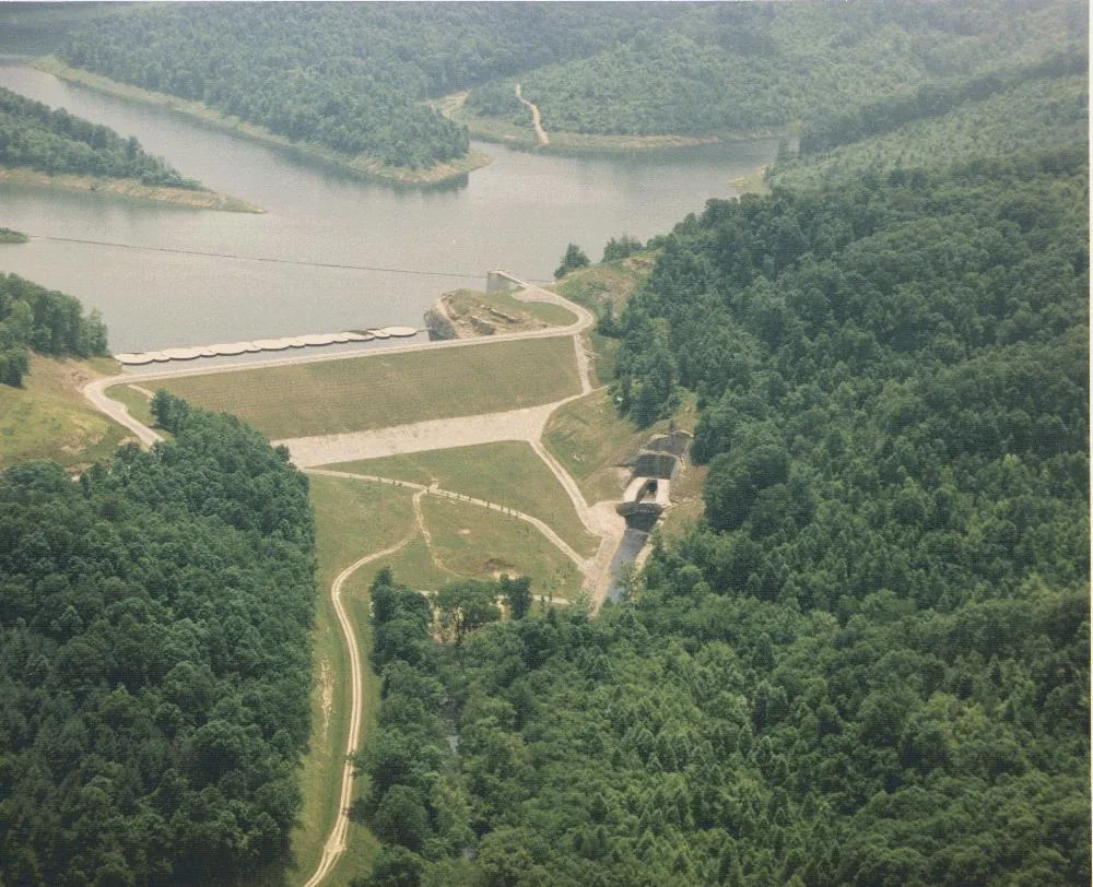 Aerial view of a lake, earth dam and forested hills