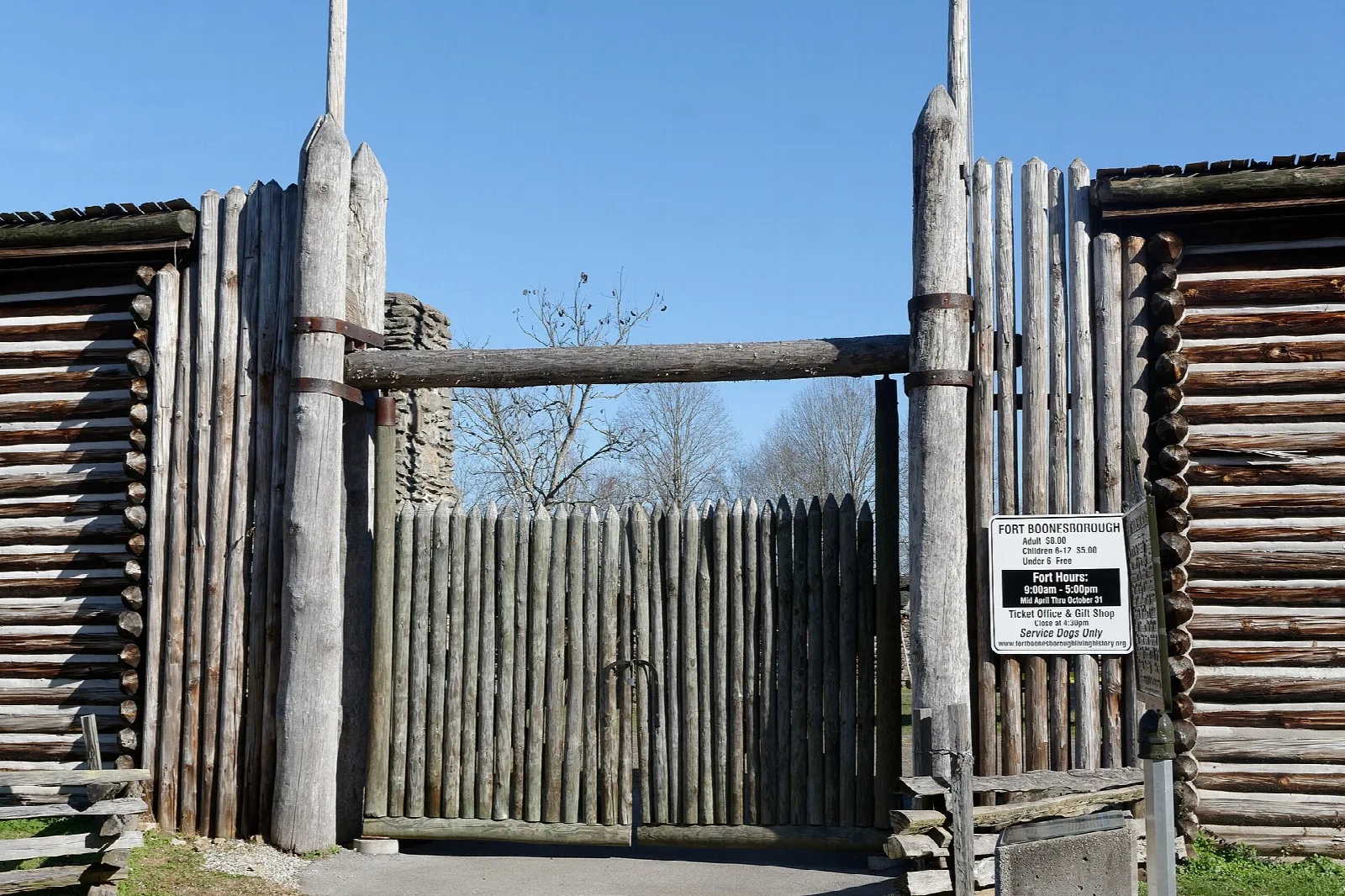 Tall log stockade gate with a posted sign