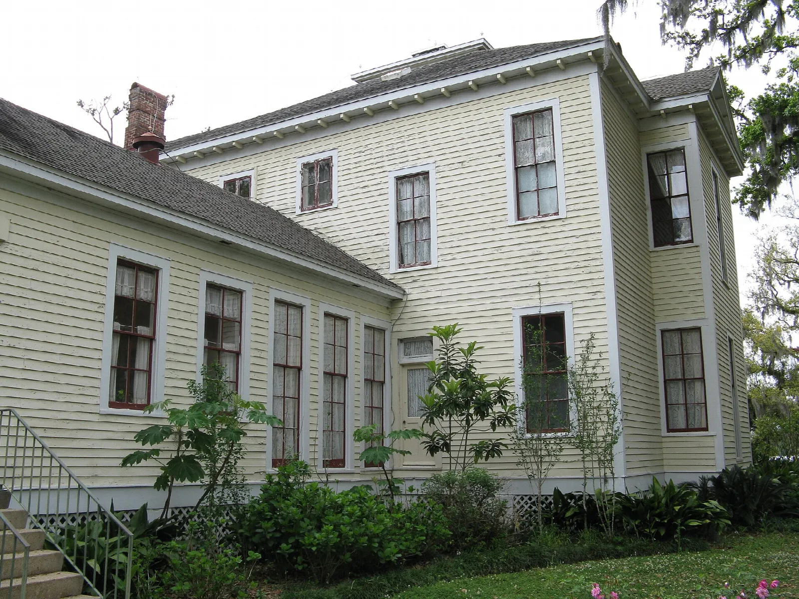 Long pale-yellow wooden house with many windows and a hip roof