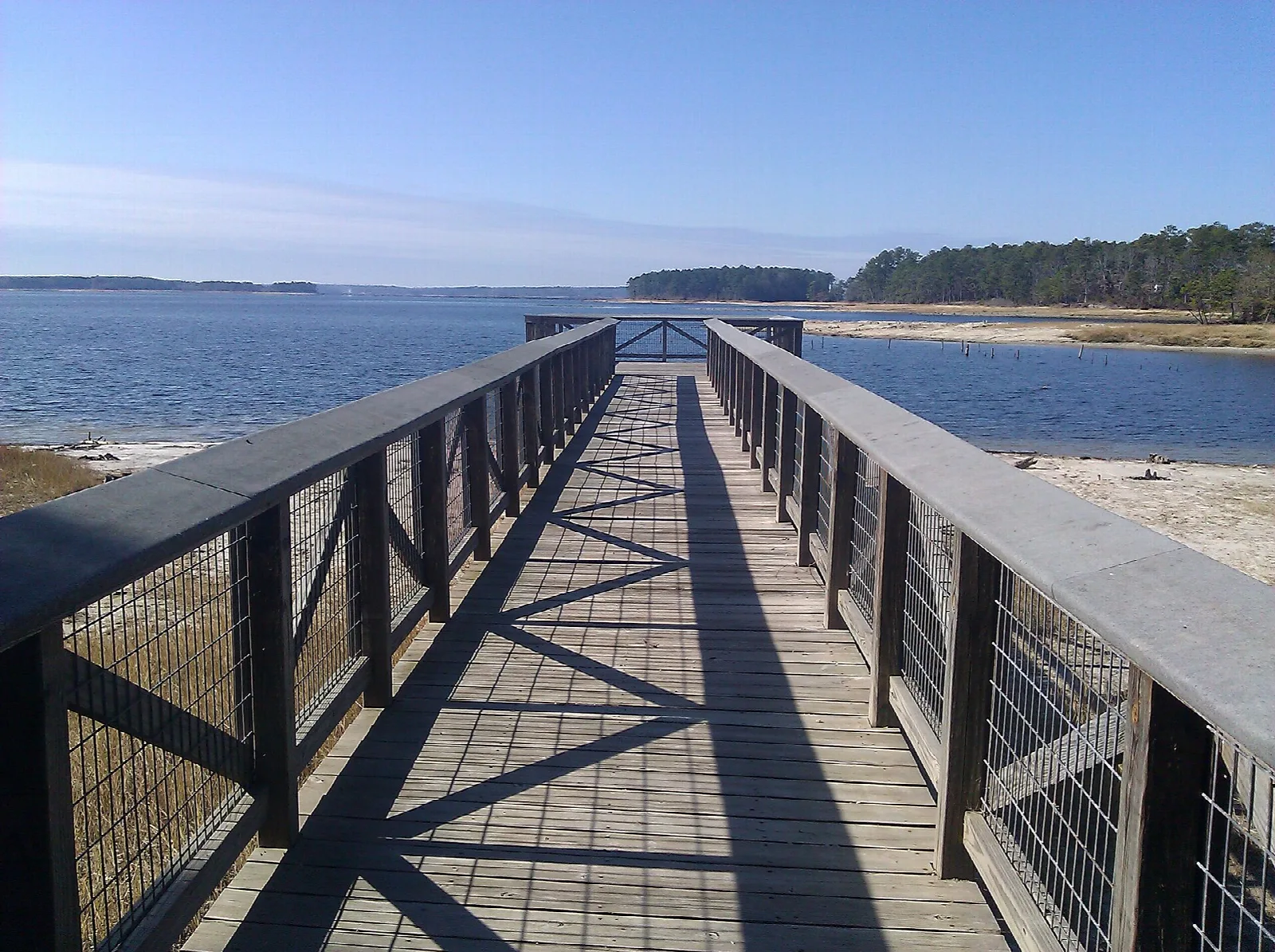 Wooden pier with railings stretching out over the reservoir