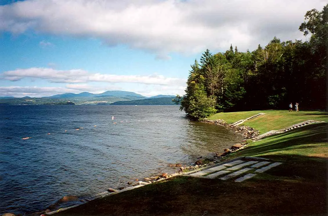 Grassy shoreline with stone steps leading down to a wide lake and distant hills