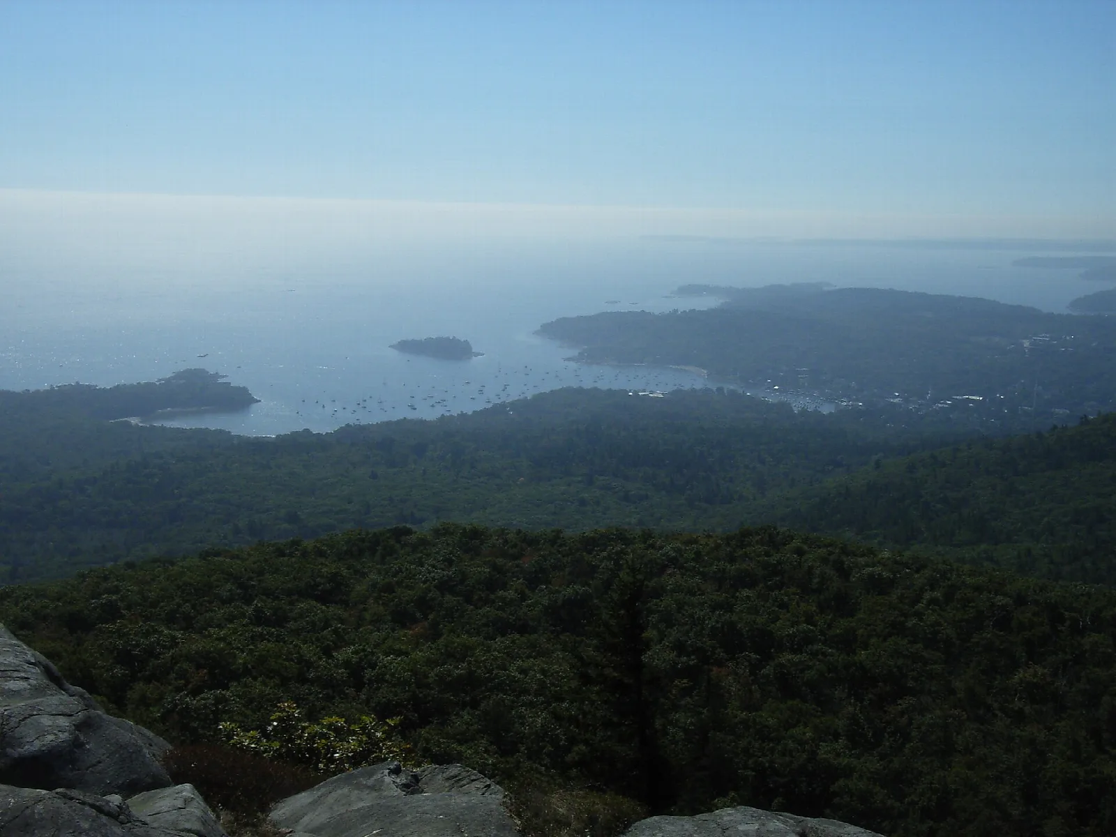 Hazy view over forest to islands and coastline from a rocky overlook