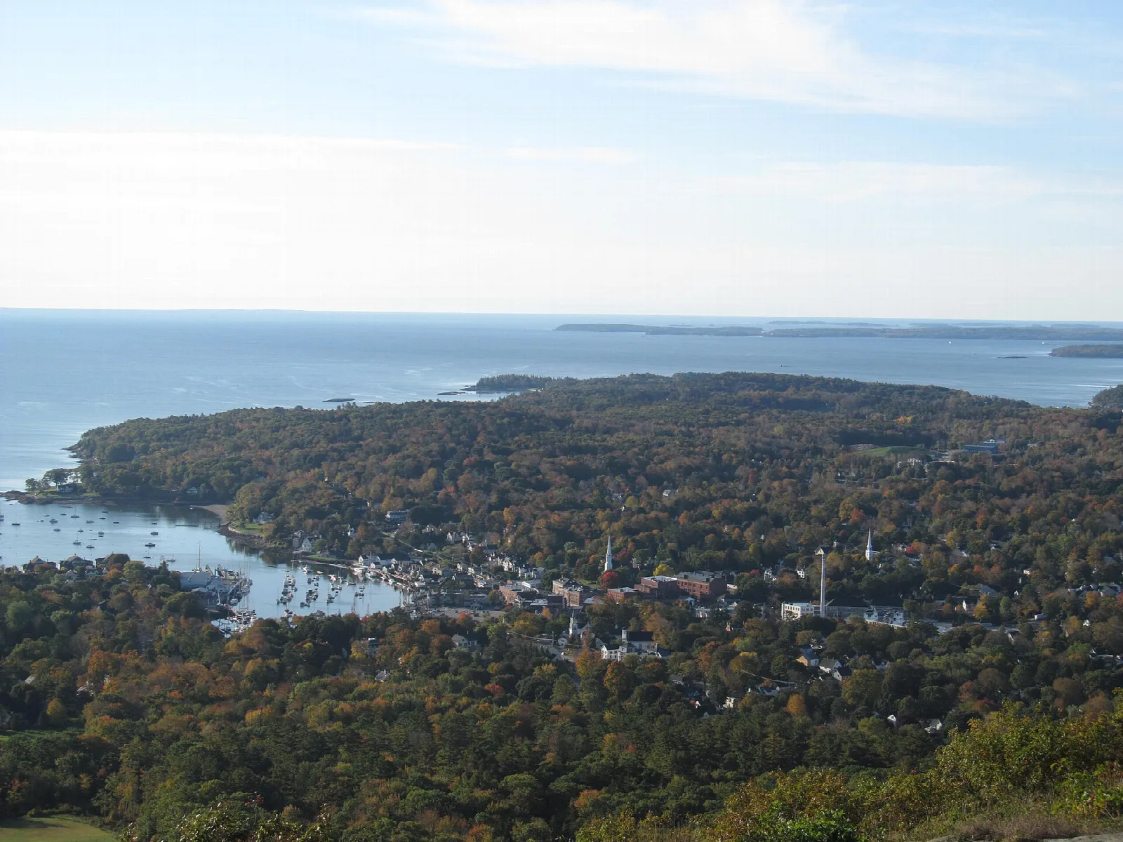 Wooded point and harbor town beside the sea seen from a high viewpoint