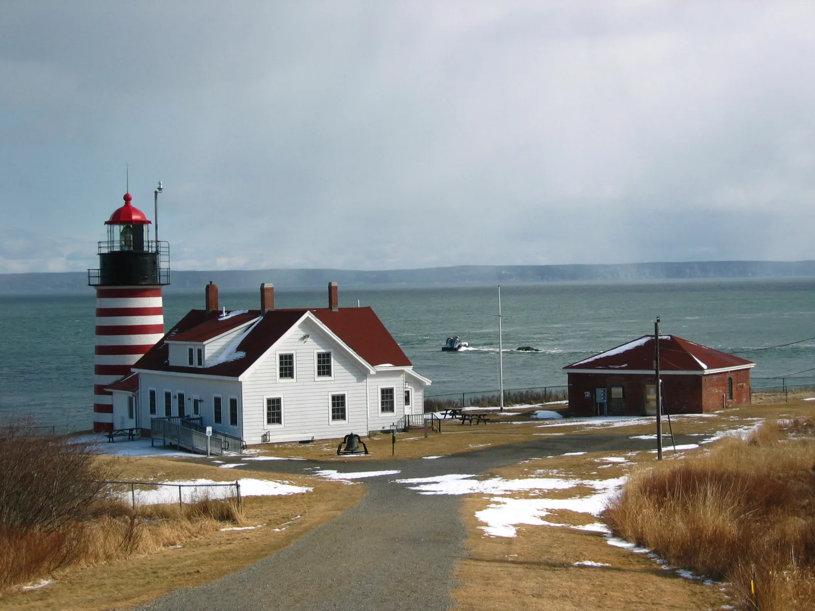 Lighthouse and keeper's house in snow with a far shore across the water