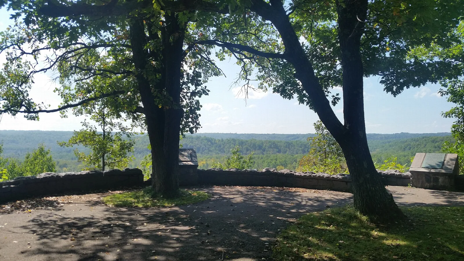 Shaded overlook with a stone wall looking over a forested valley