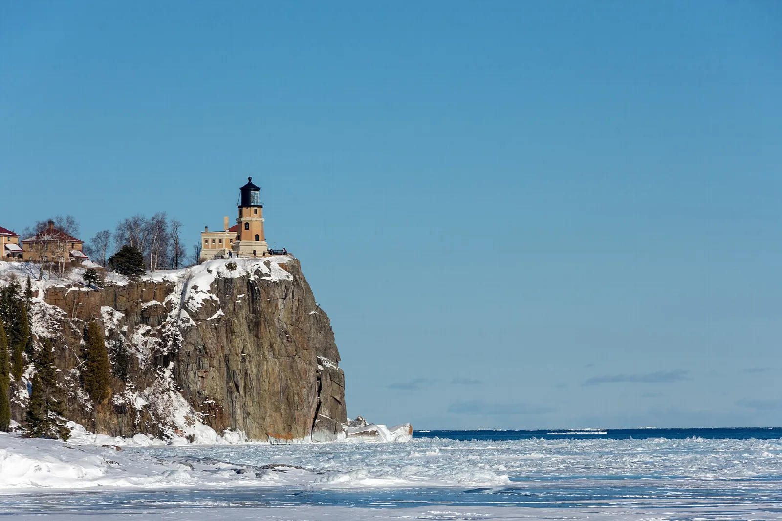 Lighthouse atop a snowy cliff beside ice-covered Lake Superior