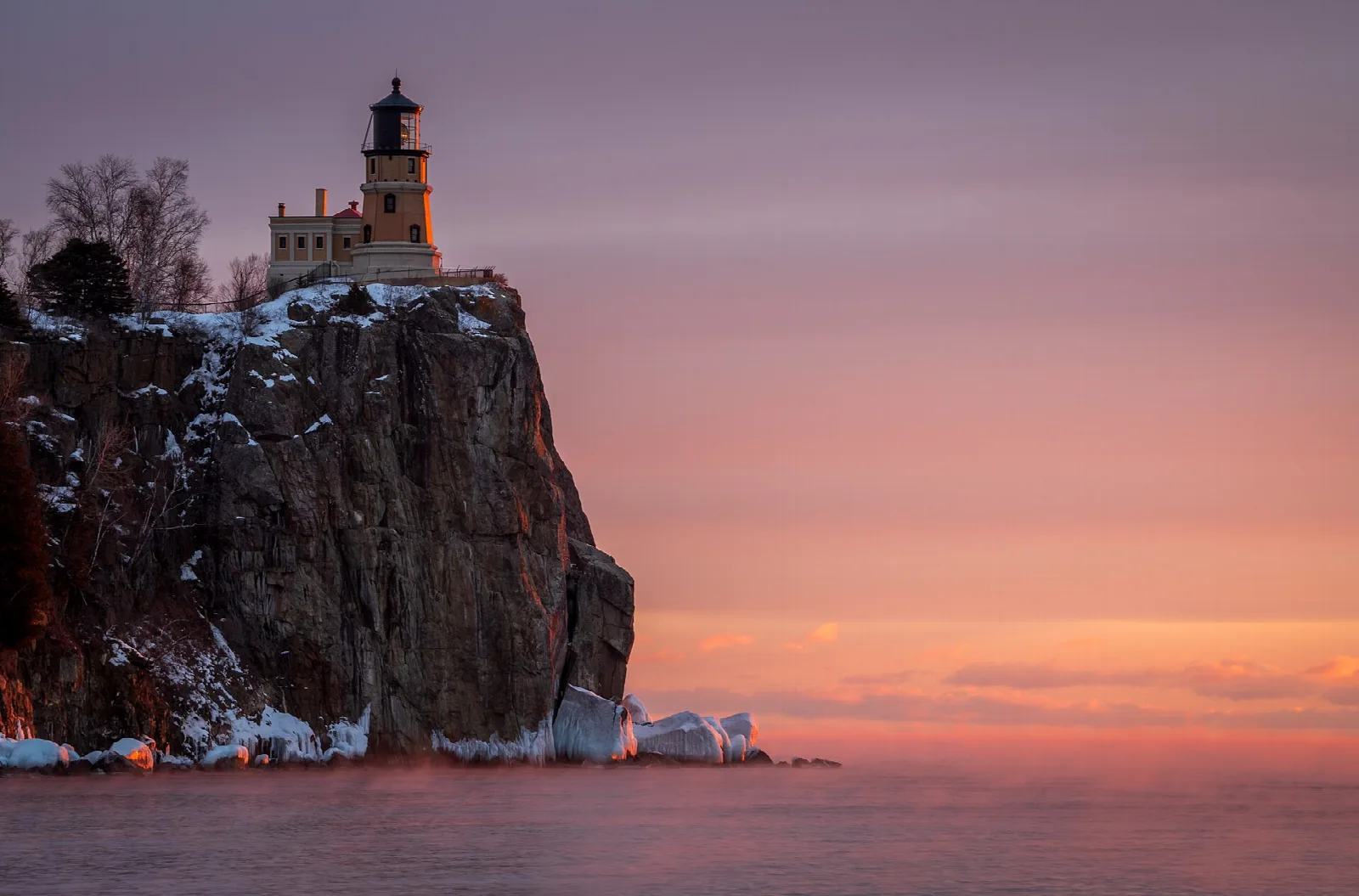 Lighthouse on a tall cliff above Lake Superior at pink sunrise