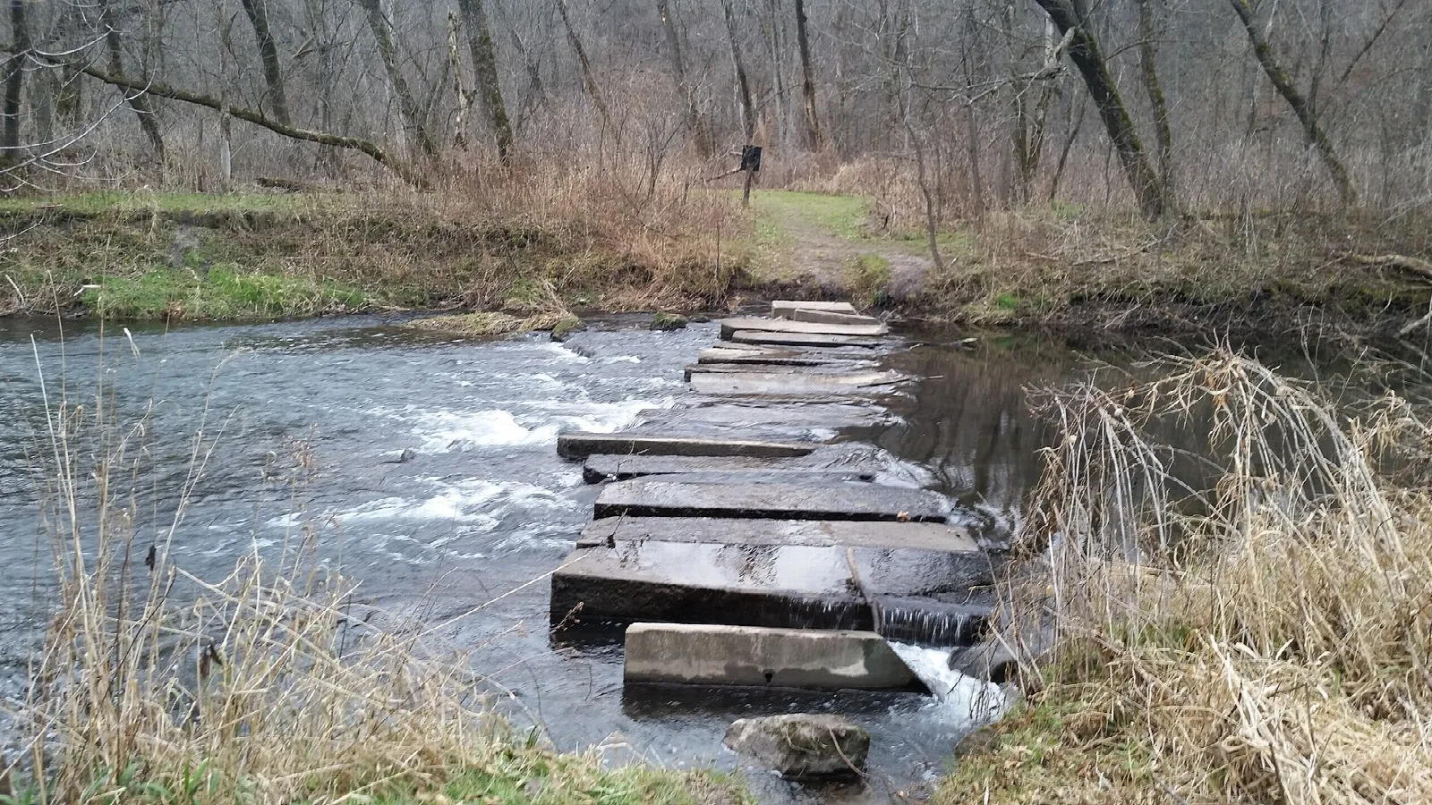 Wooden plank stepping stones crossing a shallow rushing river