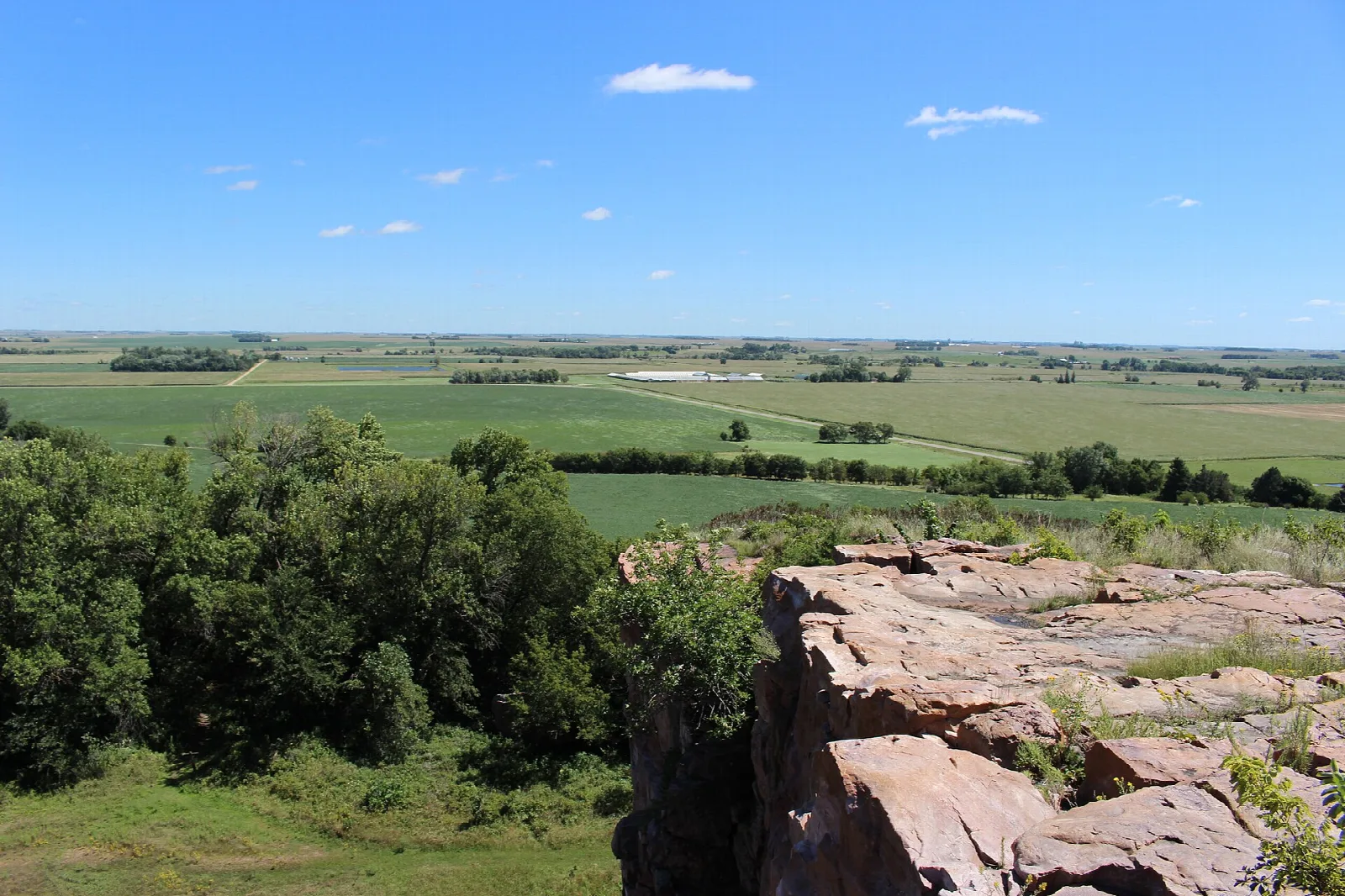 Rock ledge and trees looking out over flat farmland