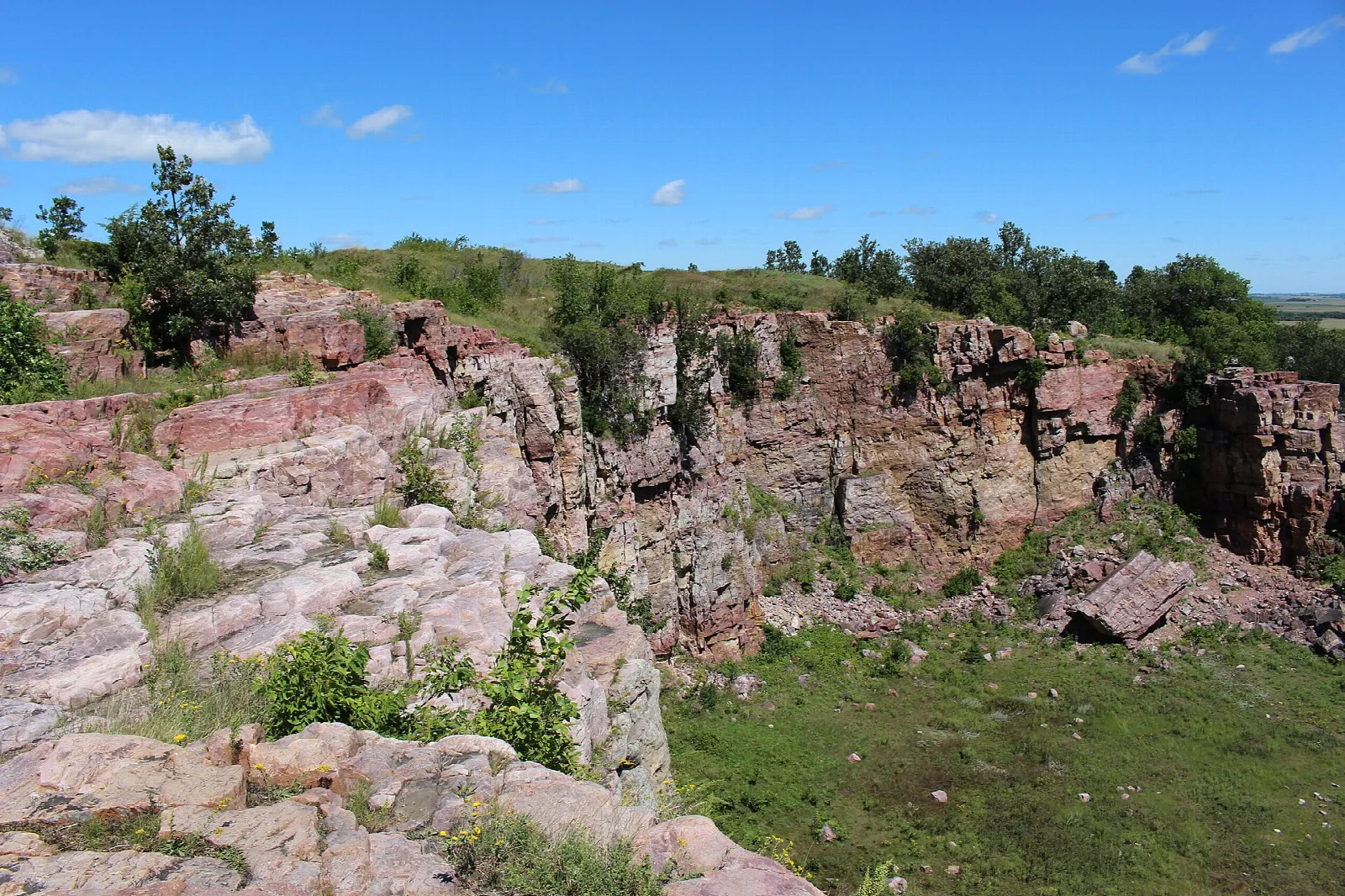 Rocky quartzite cliff edge above green prairie