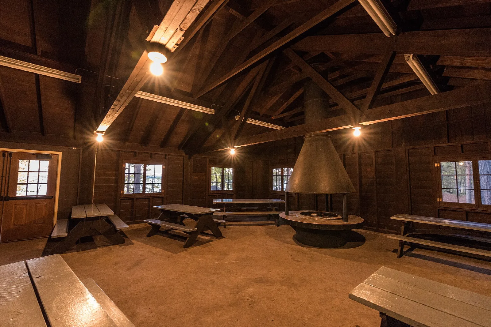 Log picnic shelter interior with benches and a central fireplace