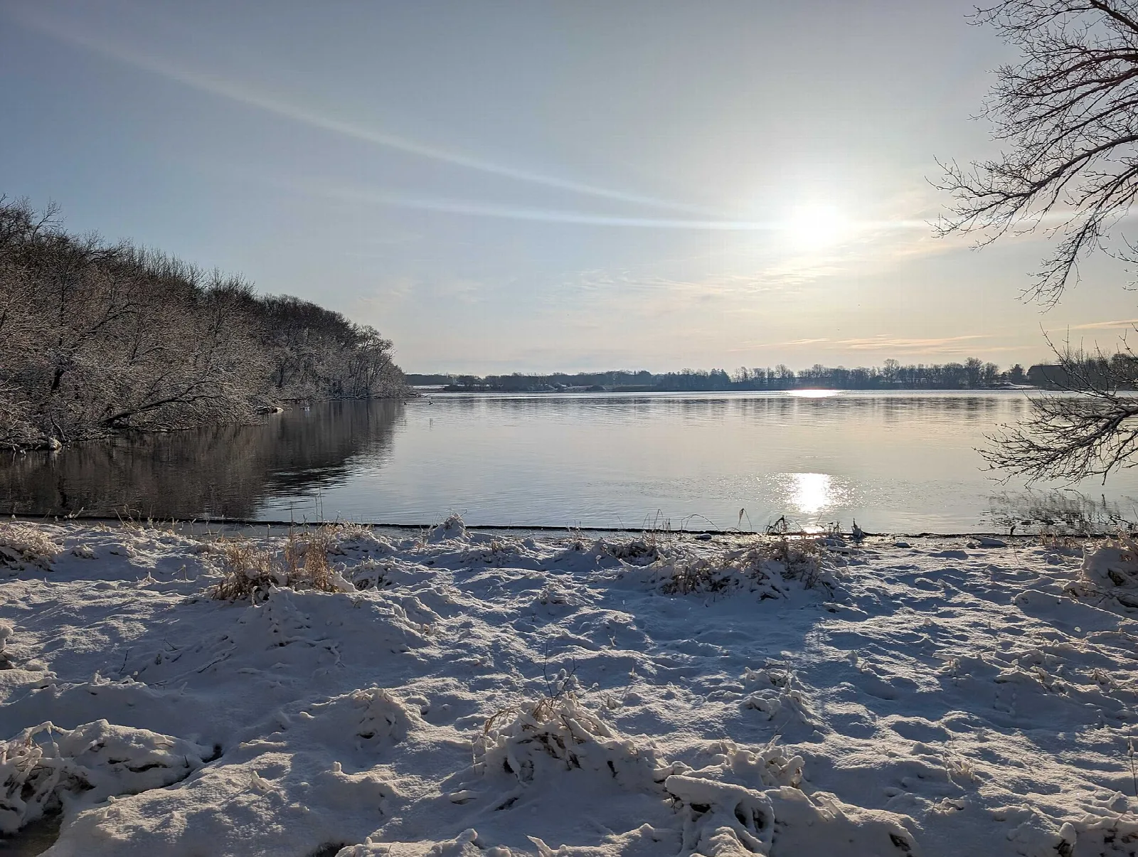 Snowy shoreline and bay of a lake with low sun