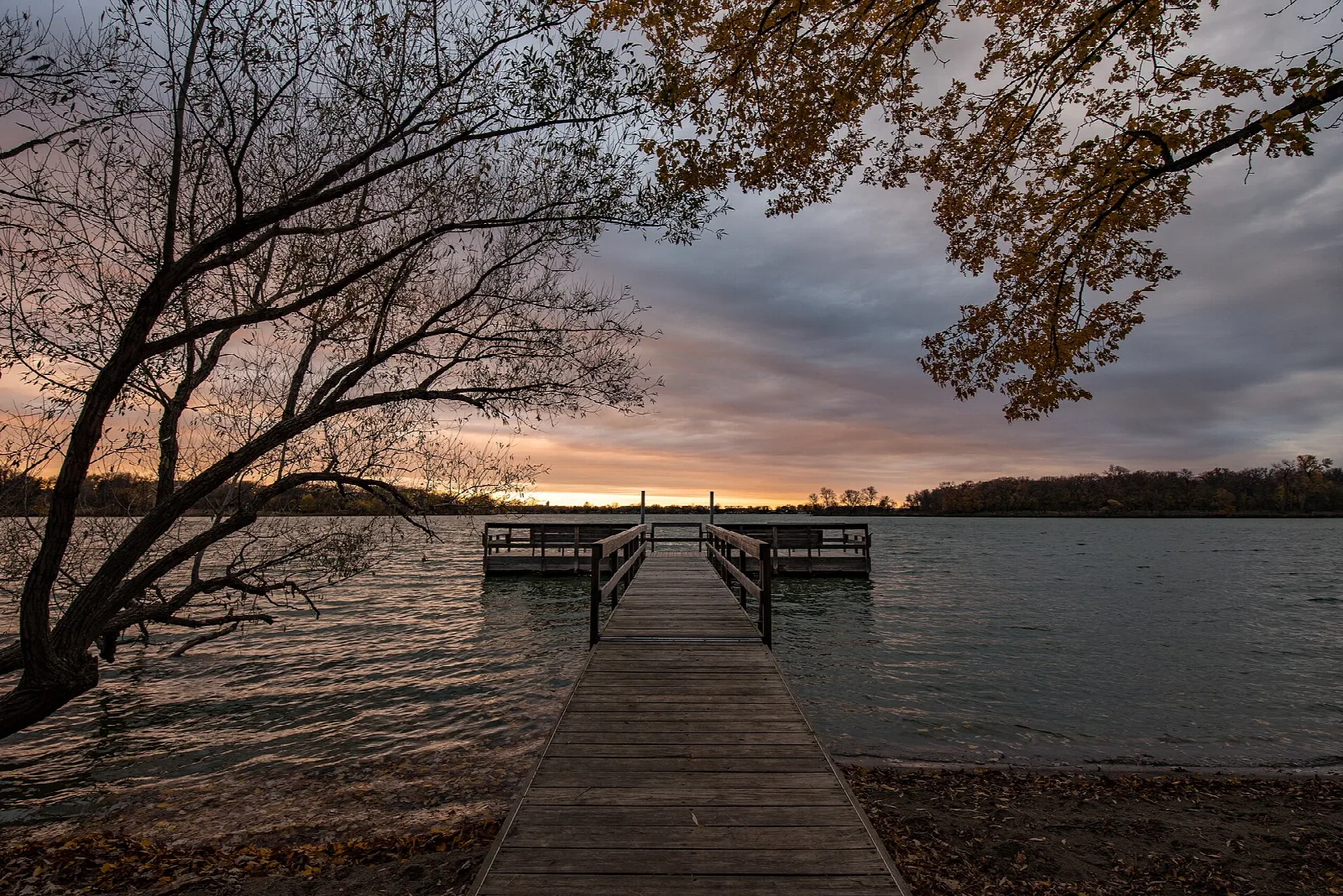 Wooden dock reaching into a lake at sunset