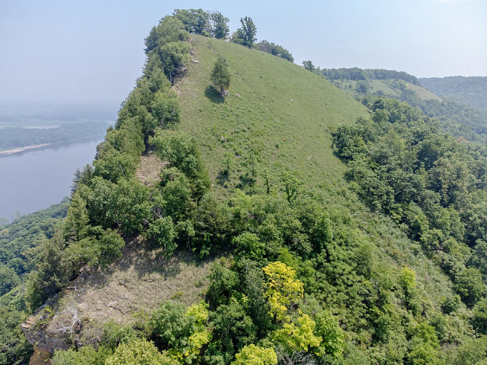Steep green bluff rising above a river valley