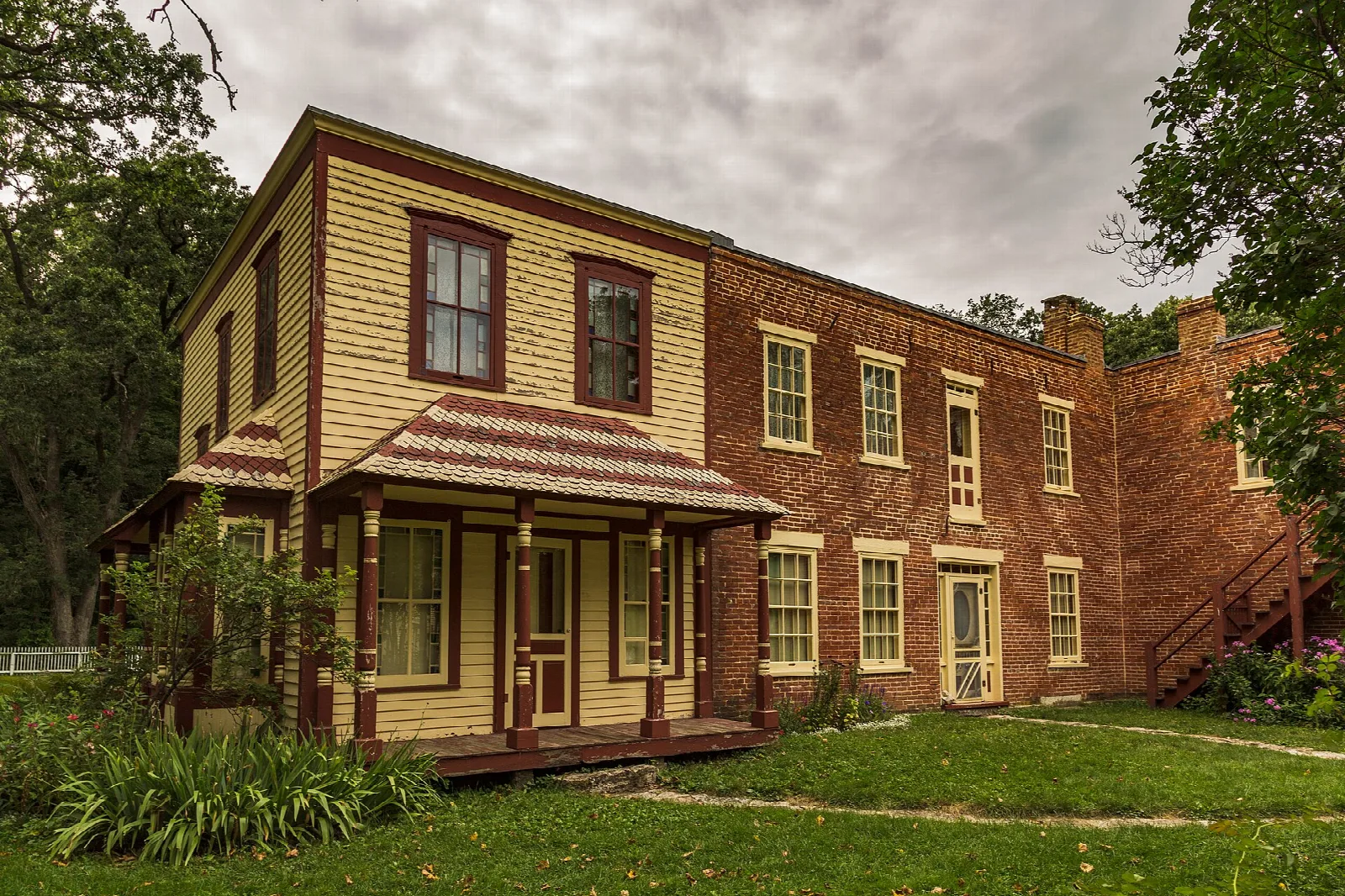 Yellow and red brick two-story house with a porch and lawn