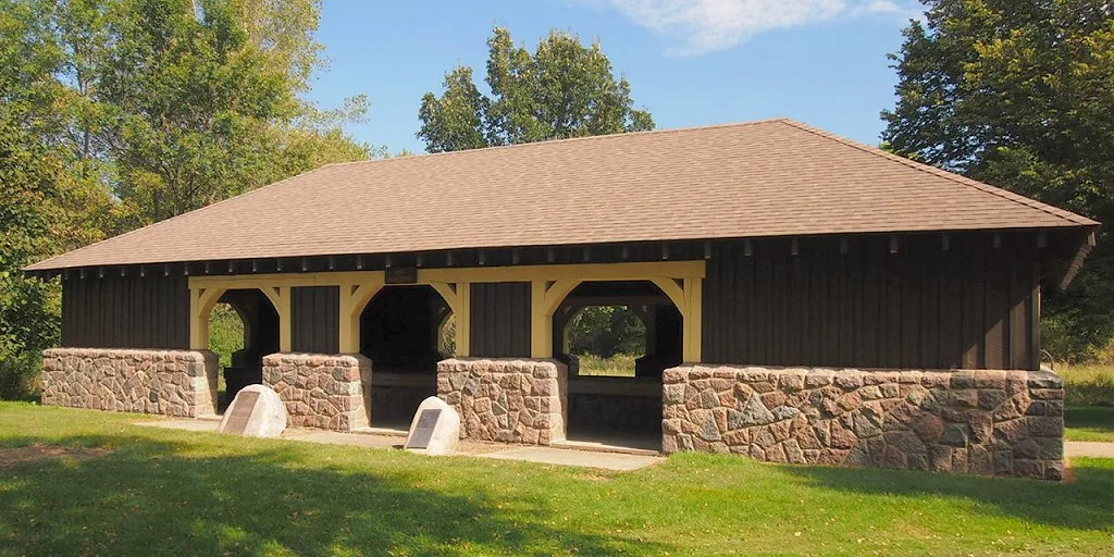 Open stone-and-timber picnic shelter on a lawn