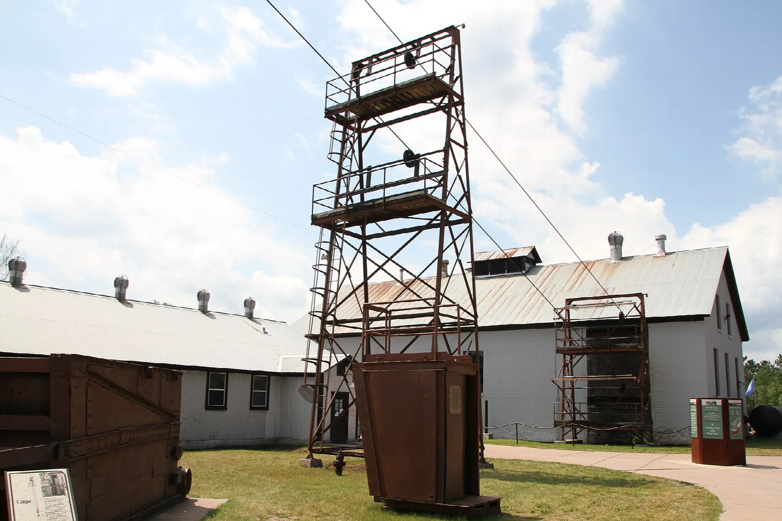 Steel headframe tower beside white mine buildings