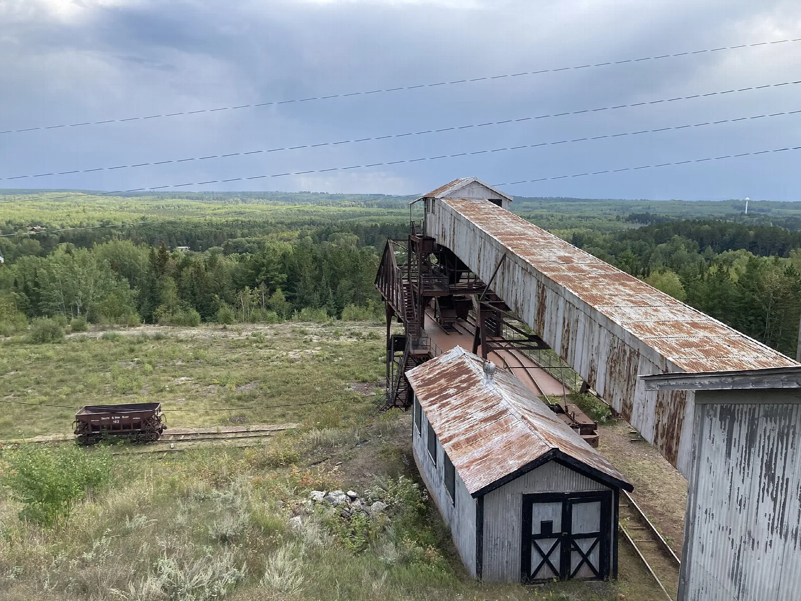 Long wooden ramp and small shed on grassland with forest behind