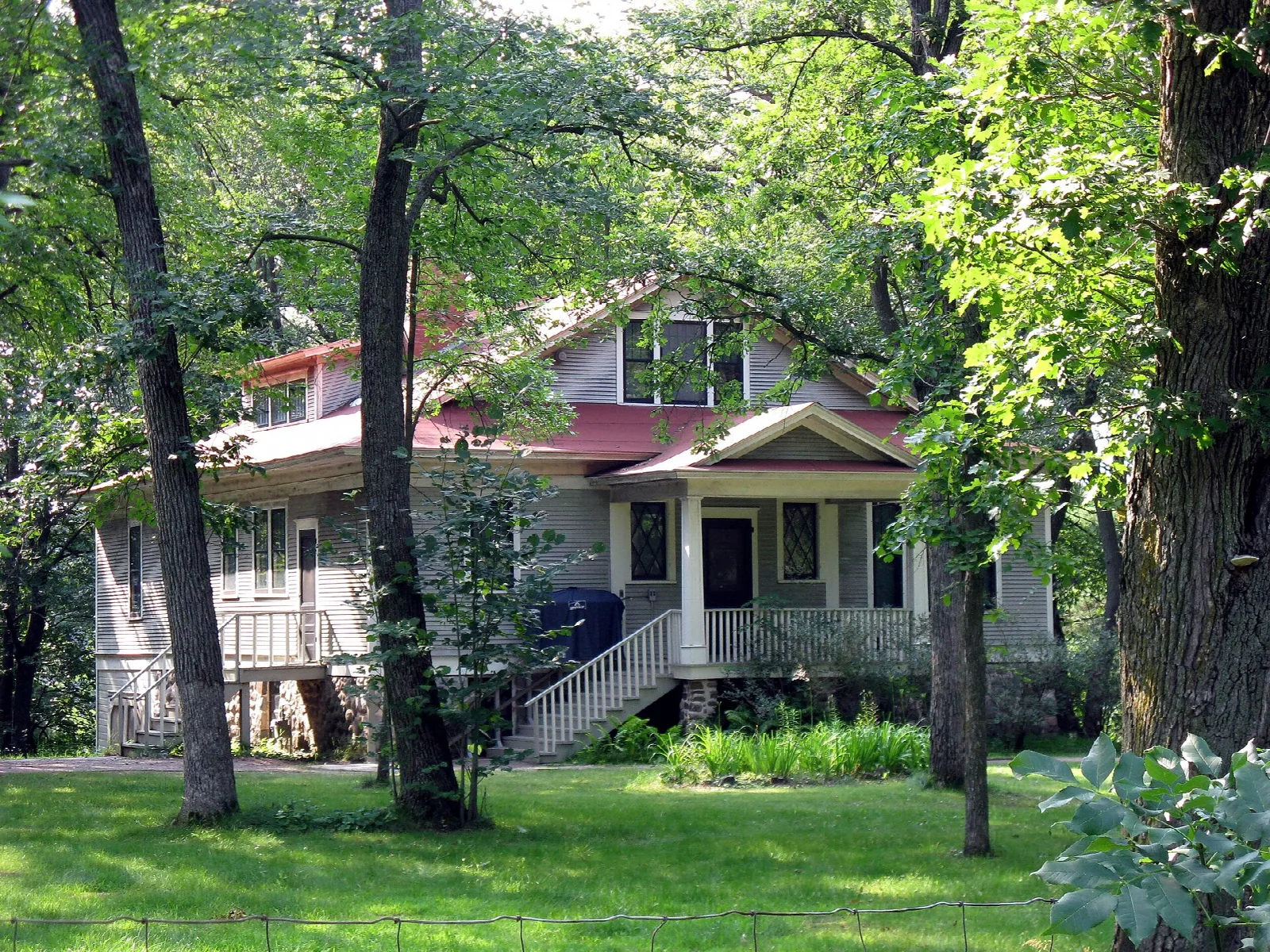 House seen through tree trunks across a shady lawn