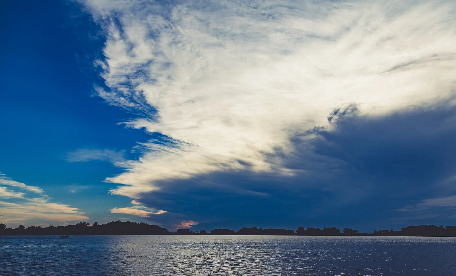 Wide lake under a deep blue sky with large clouds