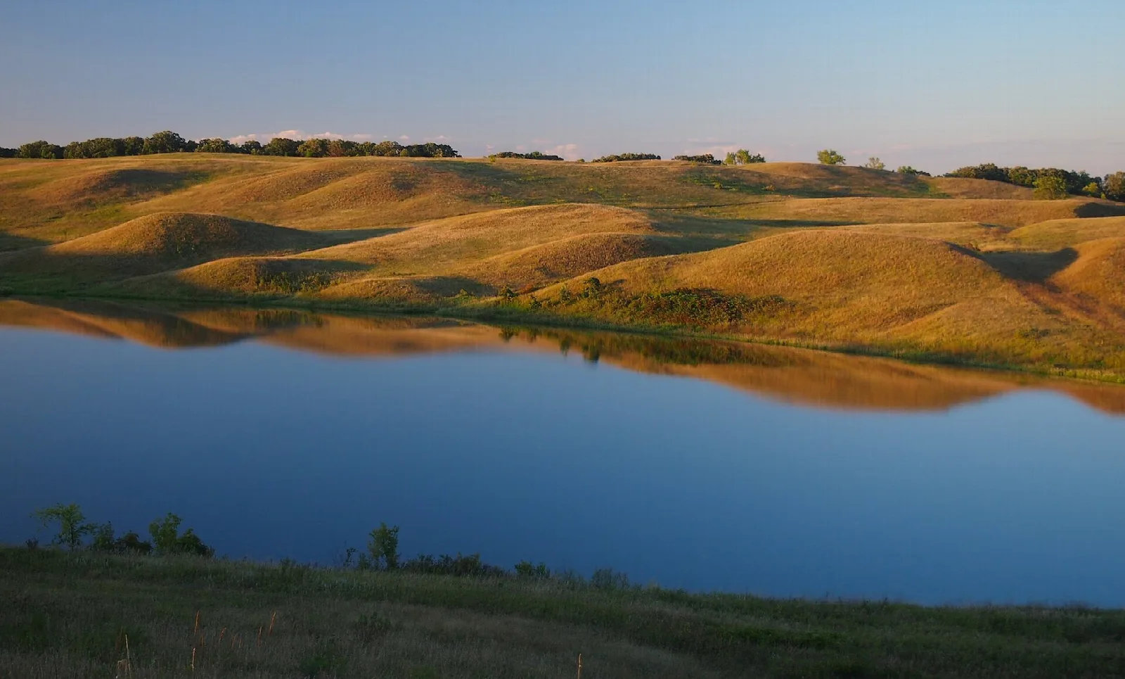 Blue lake below rolling golden prairie hills