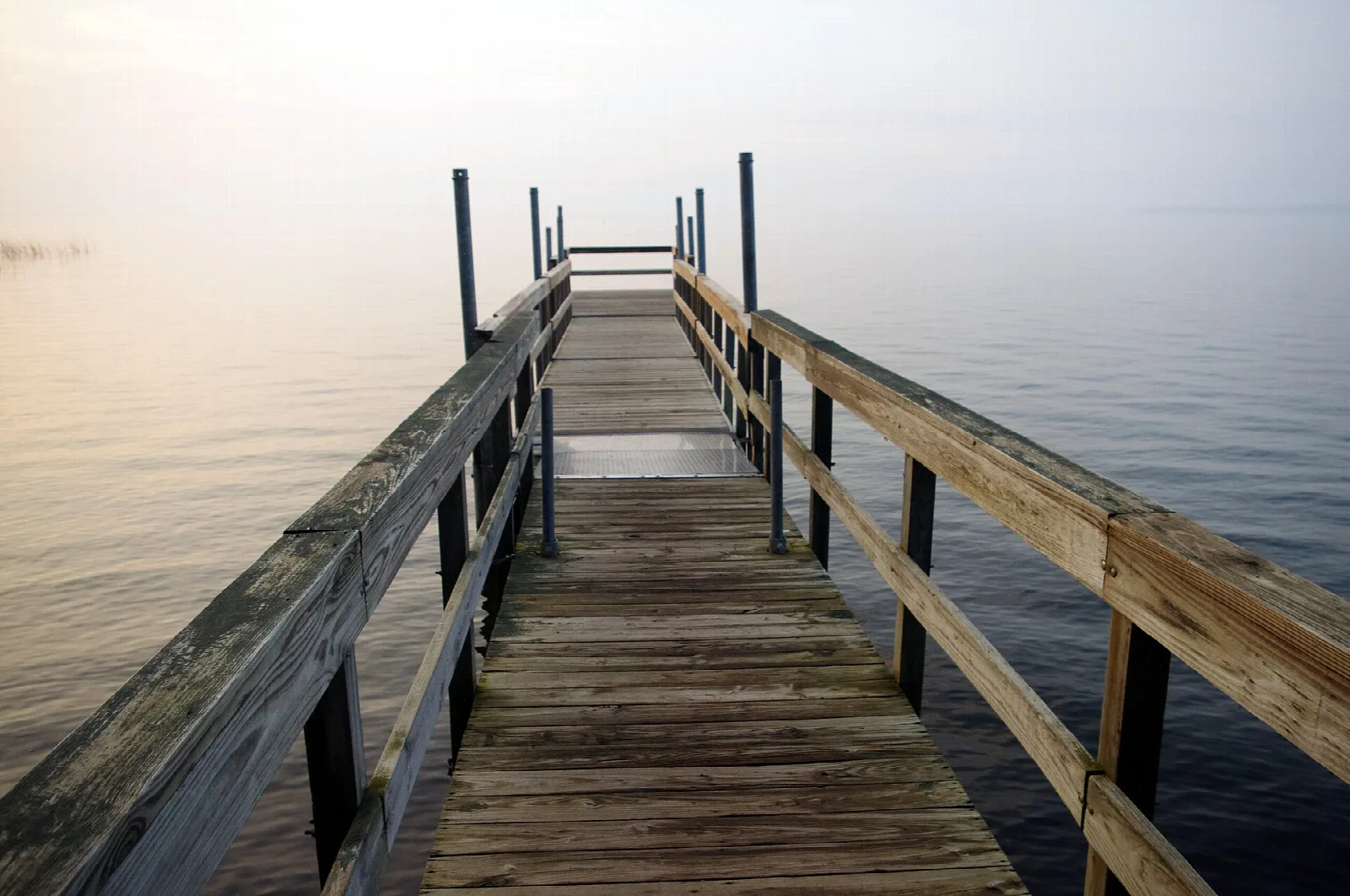 Wooden pier stretching out over misty lake water