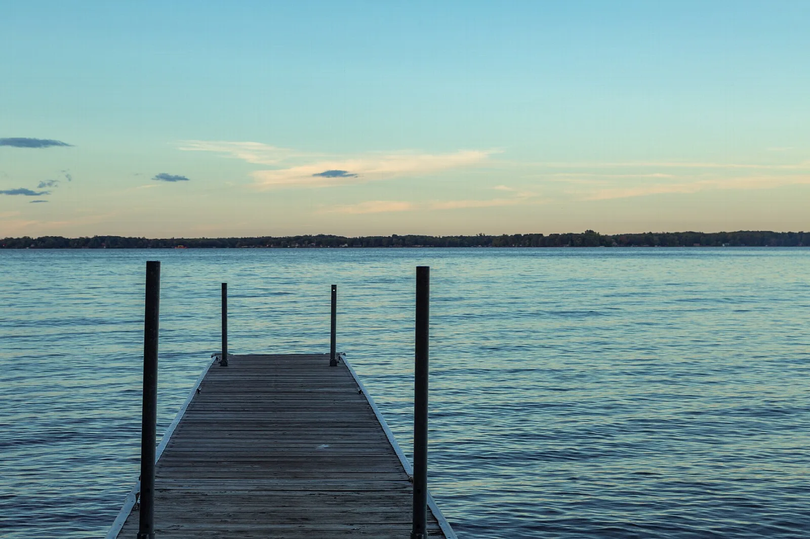 Wooden dock reaching into a calm lake at dusk