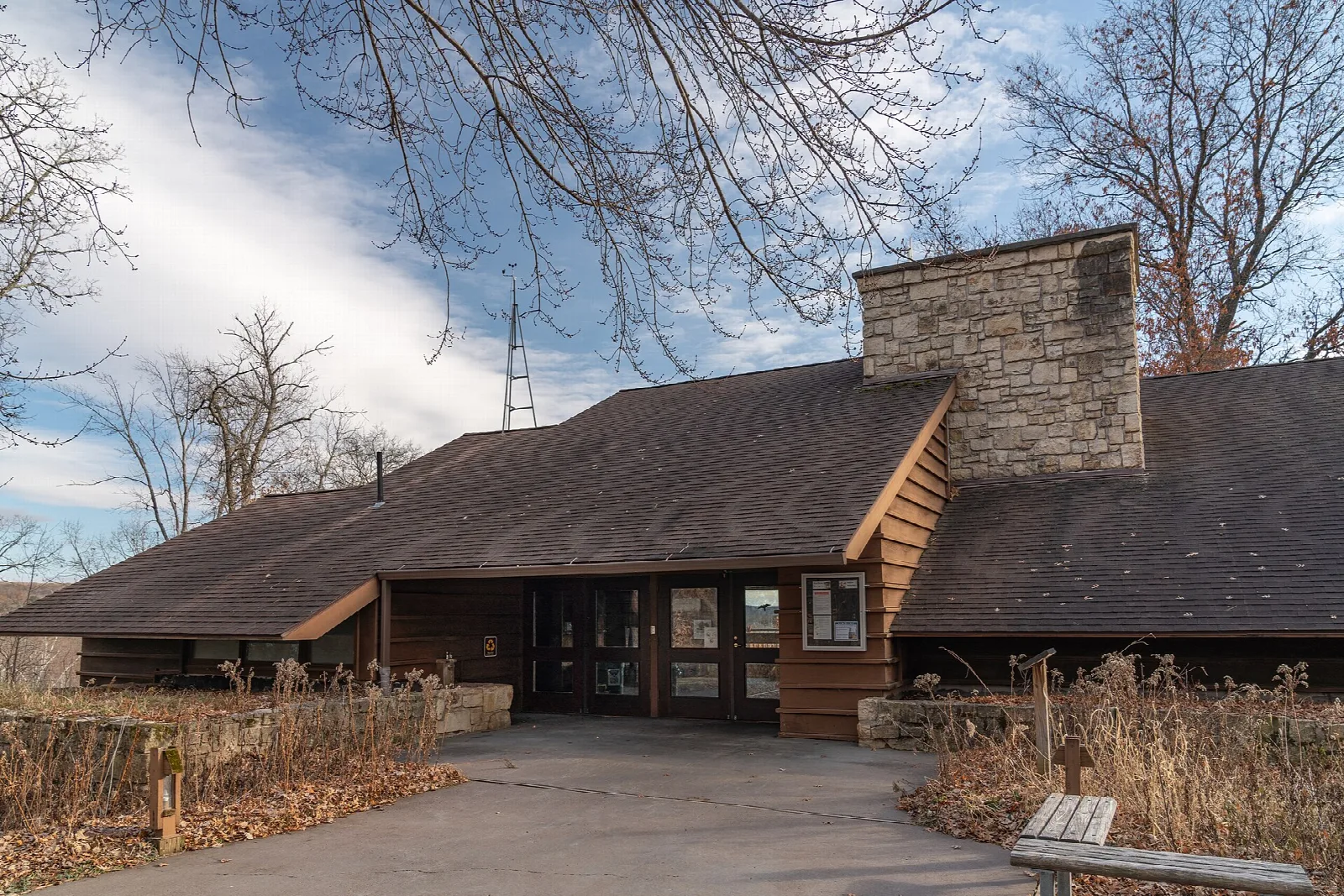 Low brown building with stone chimney and paved walk