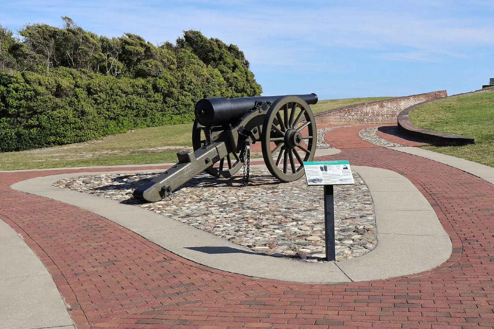 Black cannon on a cobbled pad beside a brick path