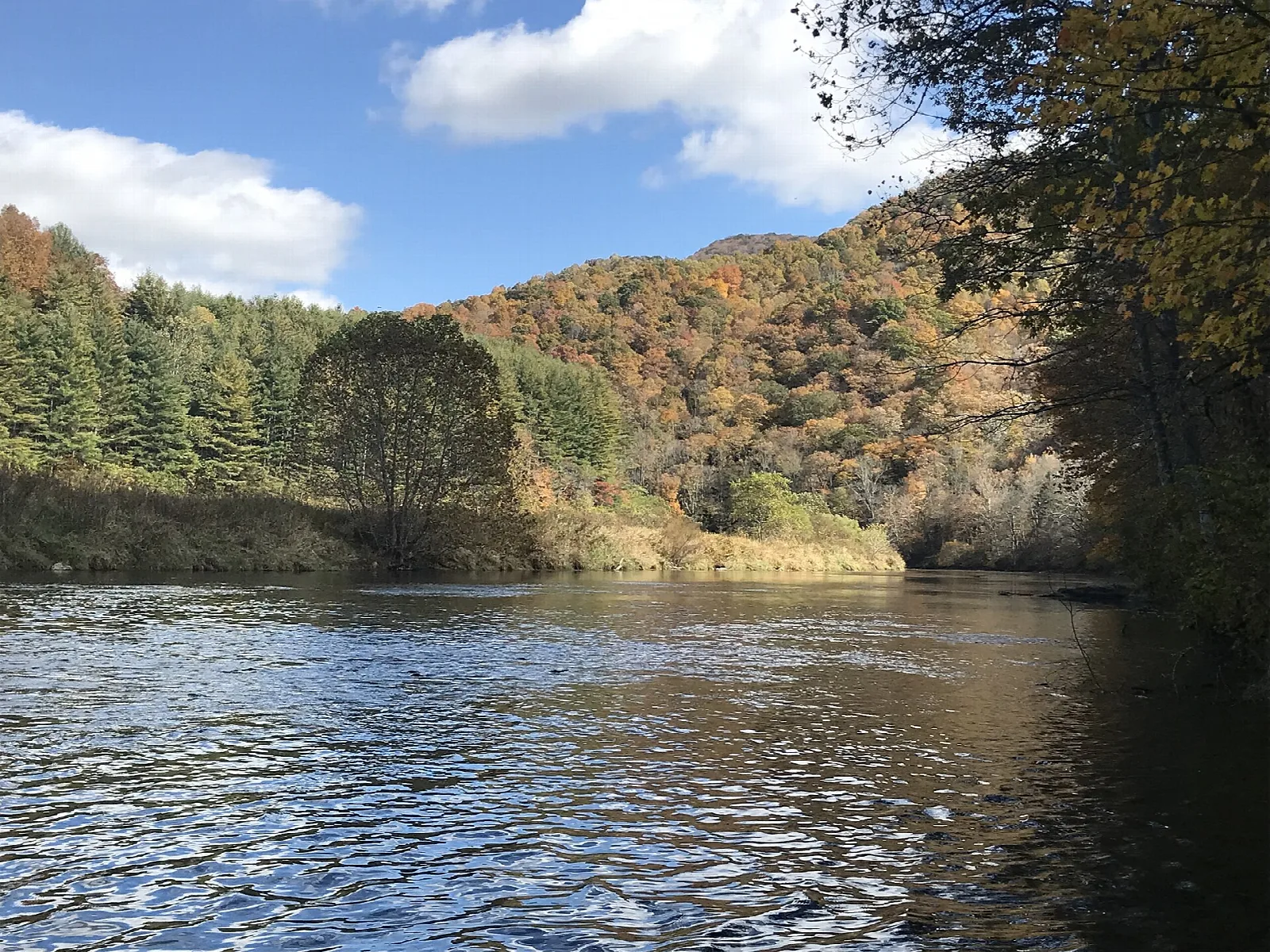 Wide river with rippled water and autumn hills behind