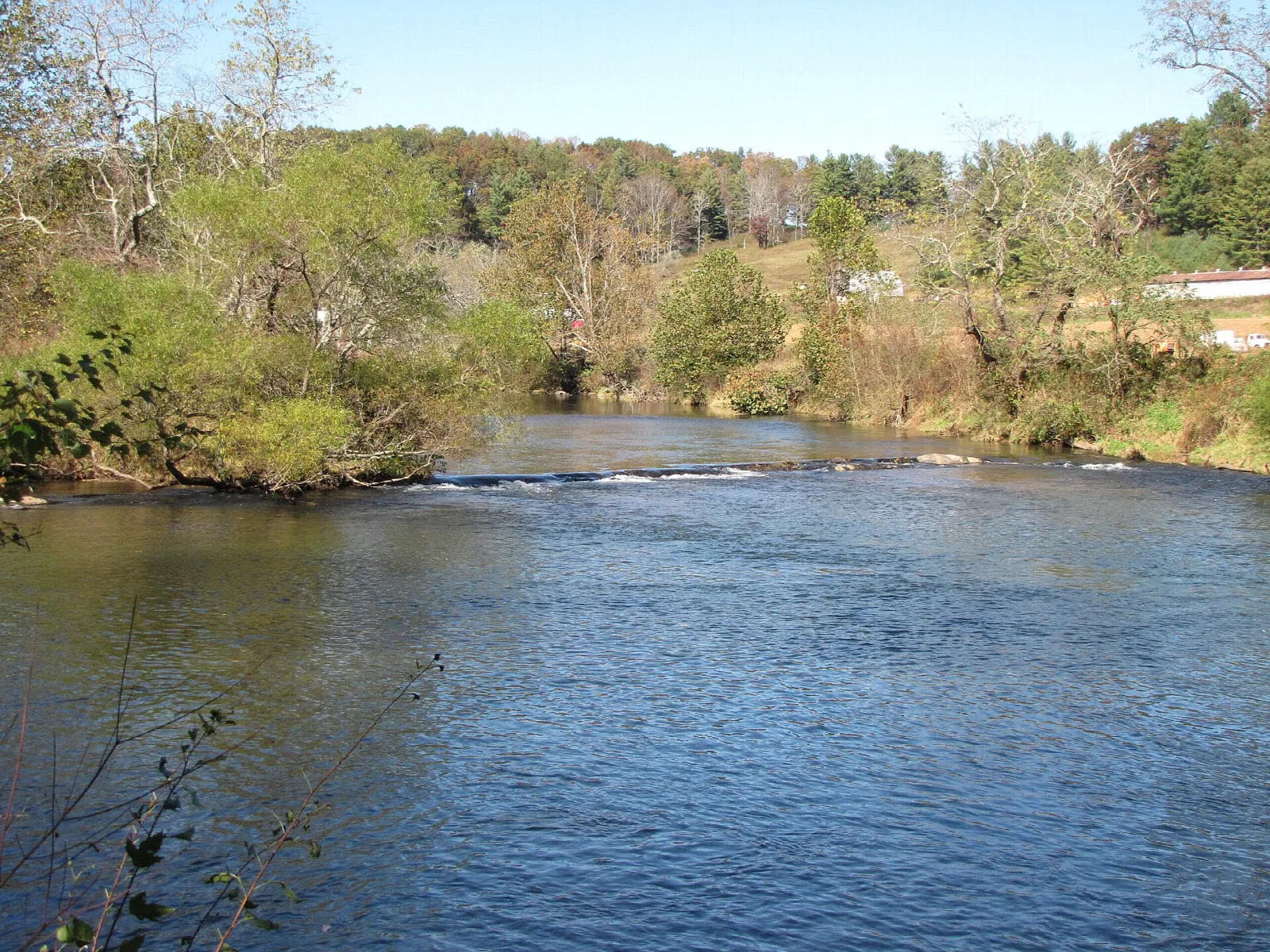 River with a low ripple across it and trees along the bank