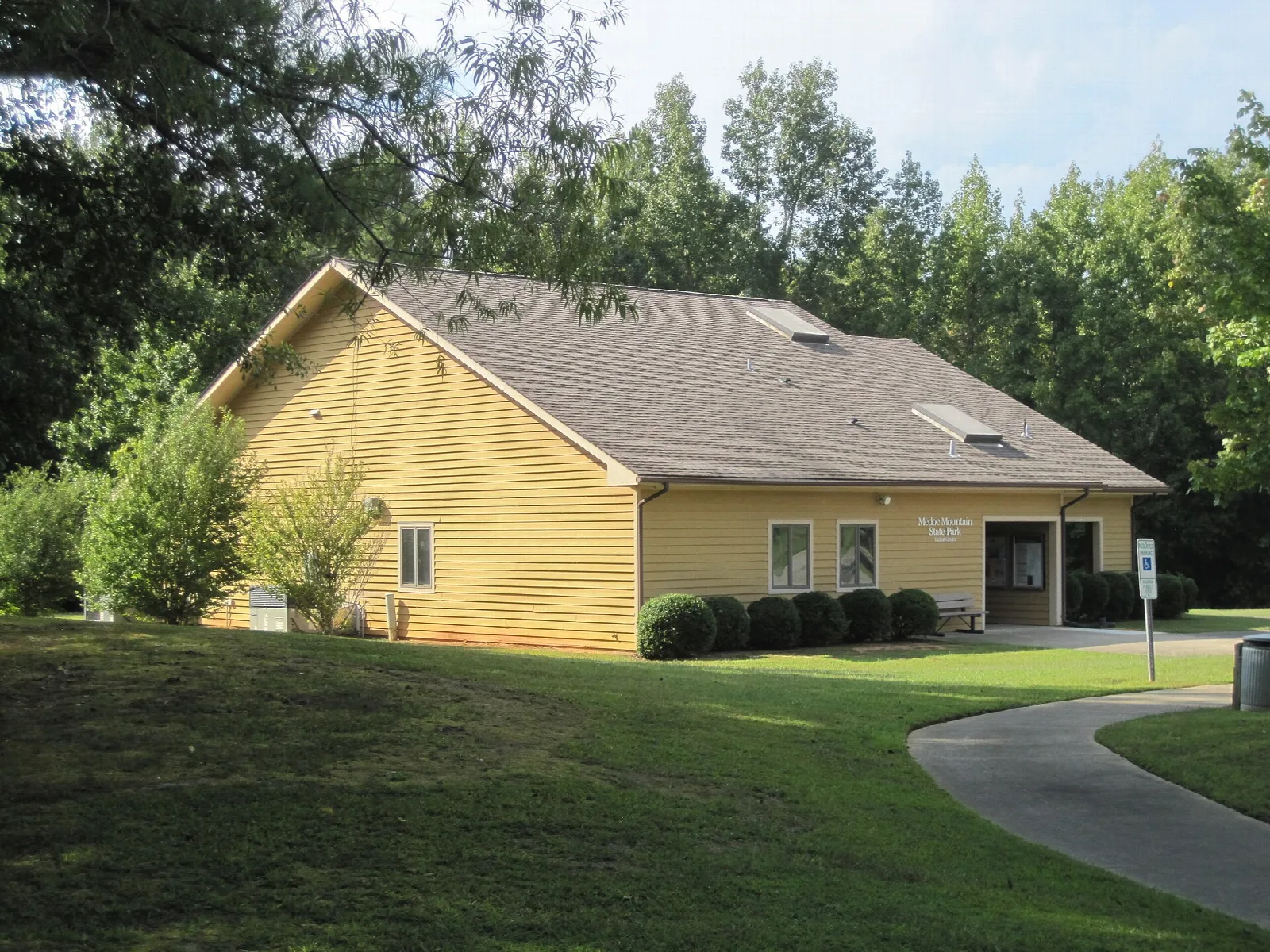 Yellow visitor center building behind a lawn and trees