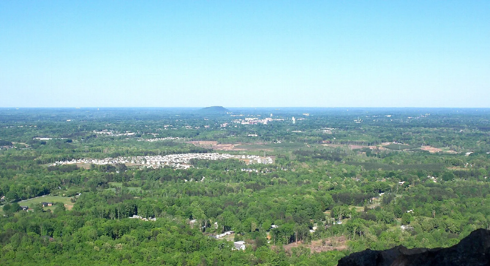 Distant town and forest seen from a high ledge