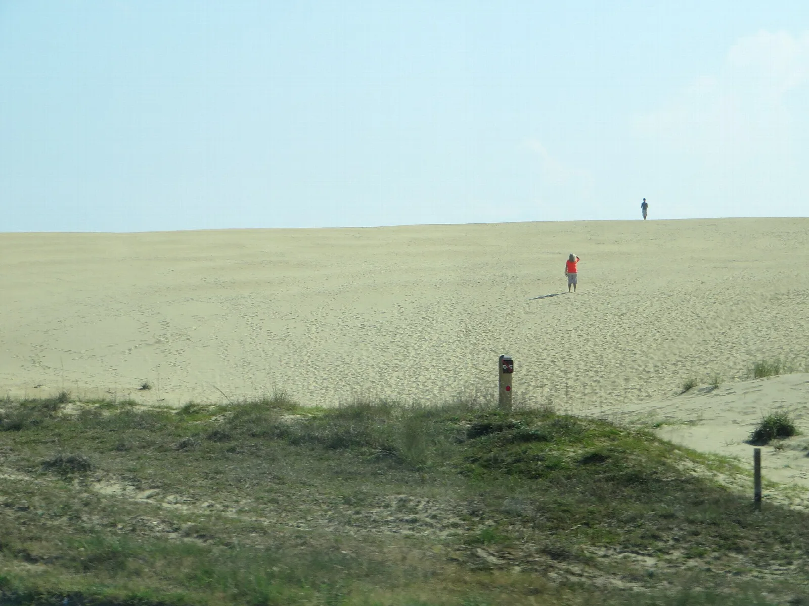 Pale sand dune slope with a few distant hikers
