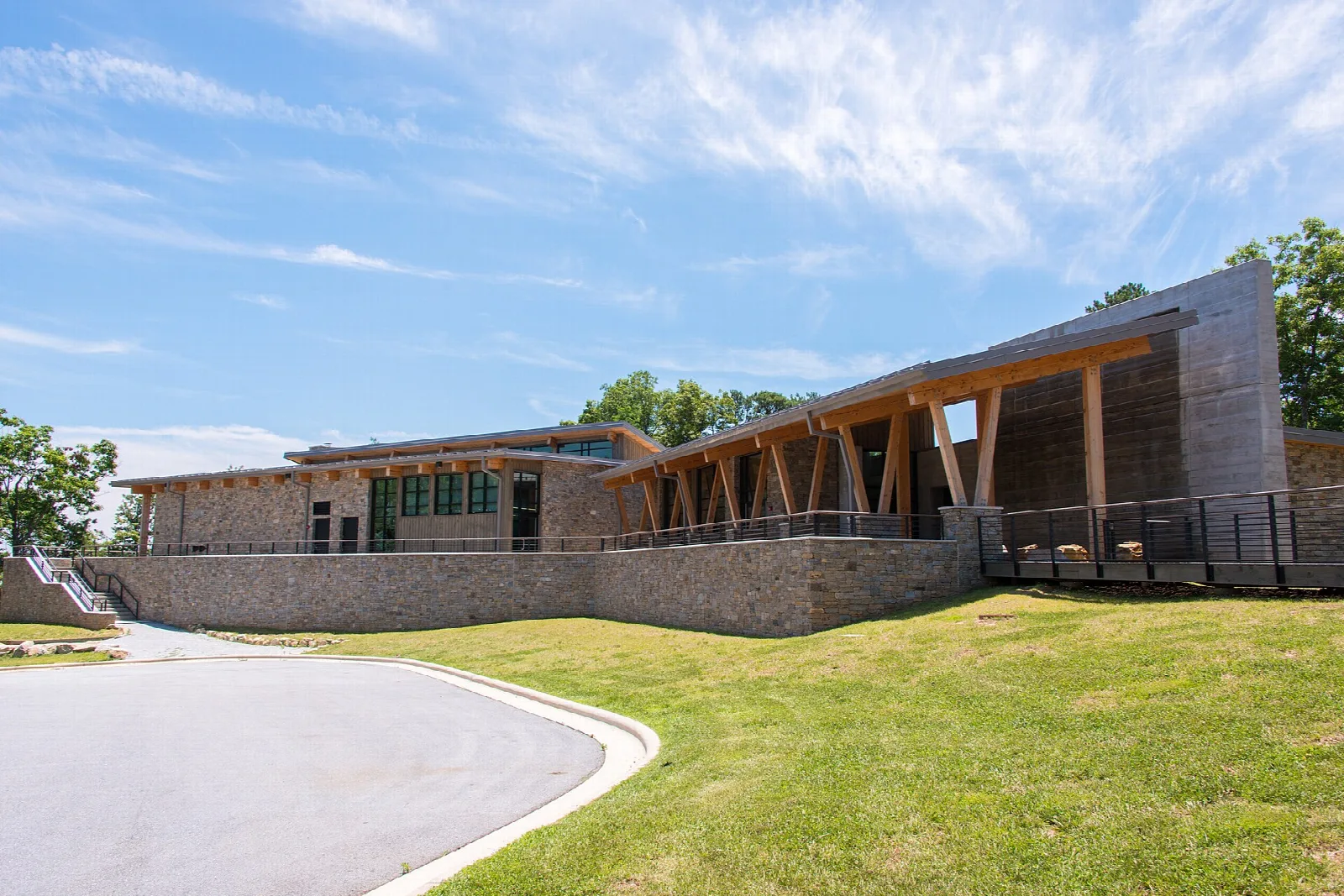 Low wood and stone visitor center building beside a lawn under a blue sky