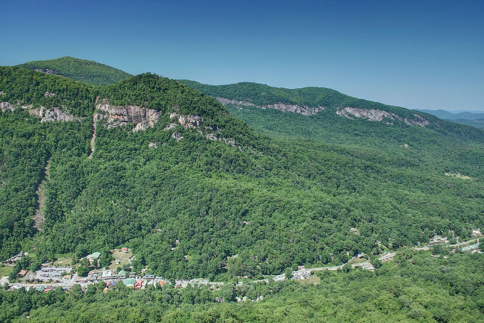 Forested mountainside with pale cliffs above a small town in the valley