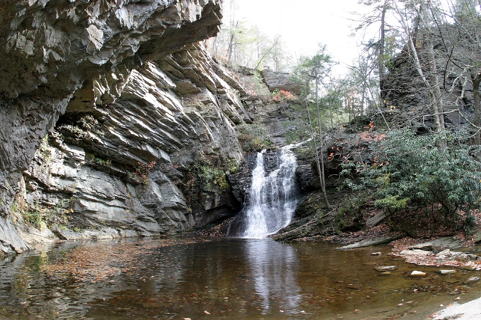 Small waterfall dropping into a pool beside a layered rock wall