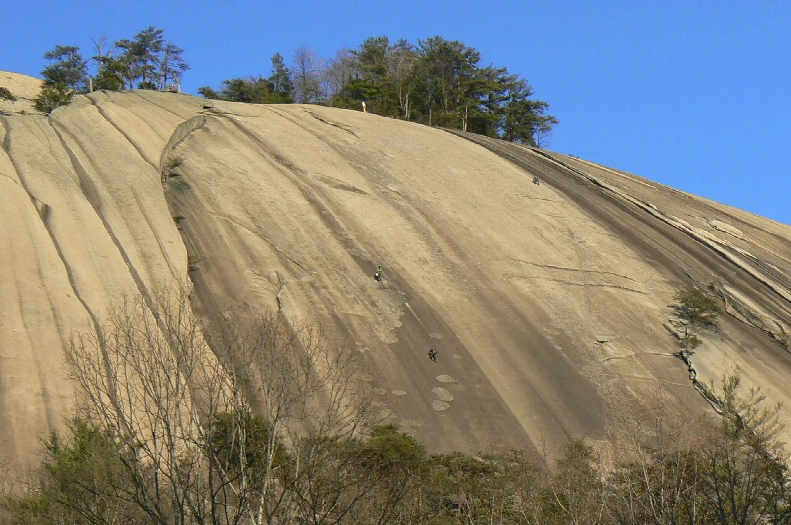 Steep pale granite dome with a few people near the base of the slope
