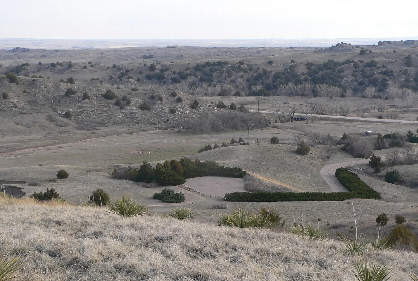 Broad prairie valley with a road and bluffs seen from a hilltop