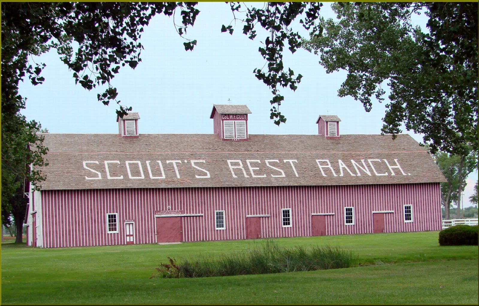 Long pink barn with Scout's Rest Ranch painted on the roof, under a blue sky