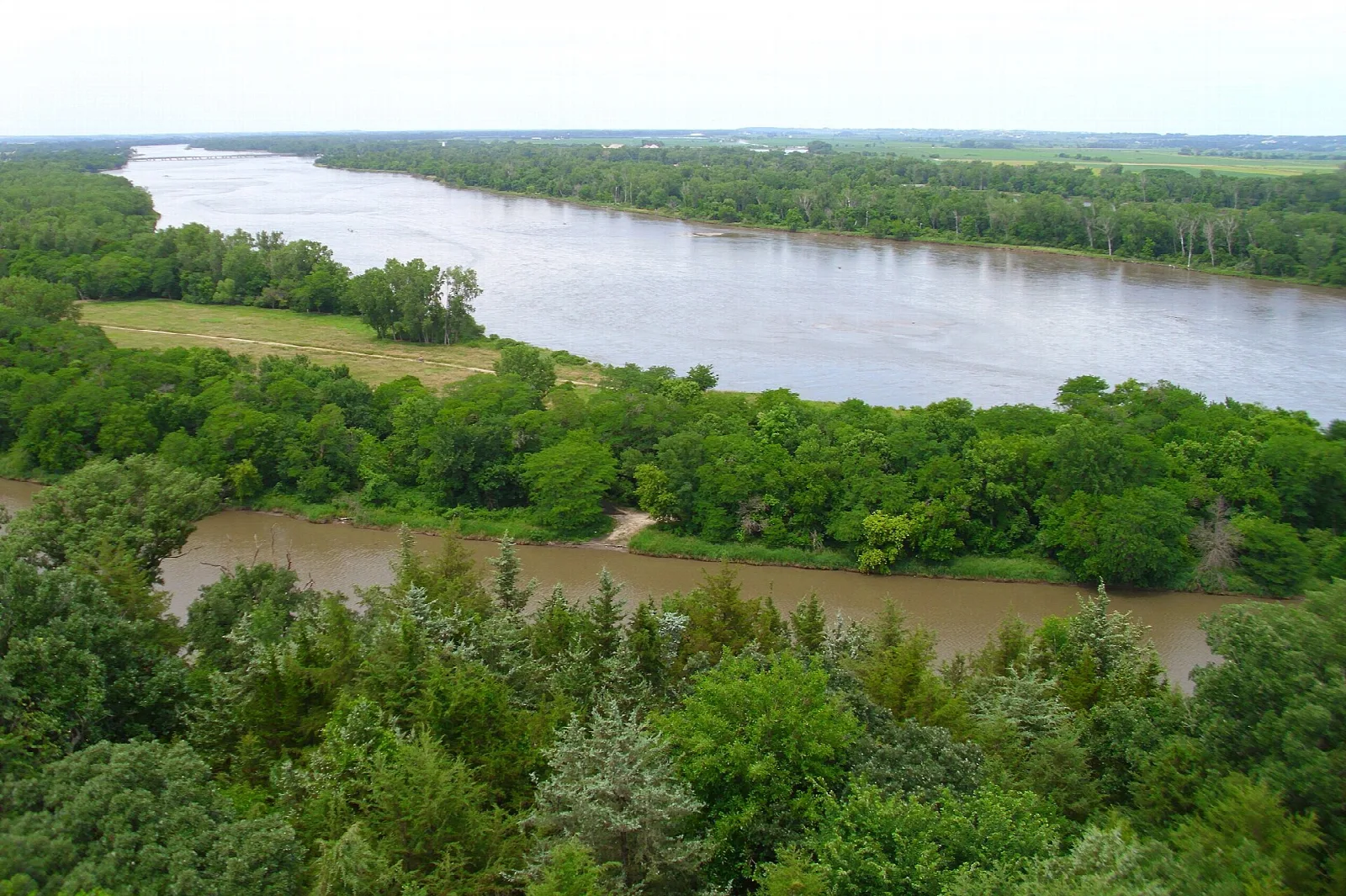 Wide brown river bending through green forest, seen from a high tower