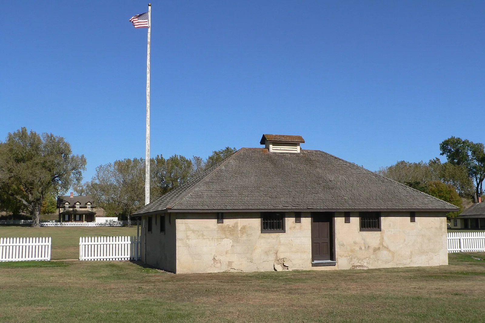 Low stone guardhouse with a flagpole behind it on a mown lawn