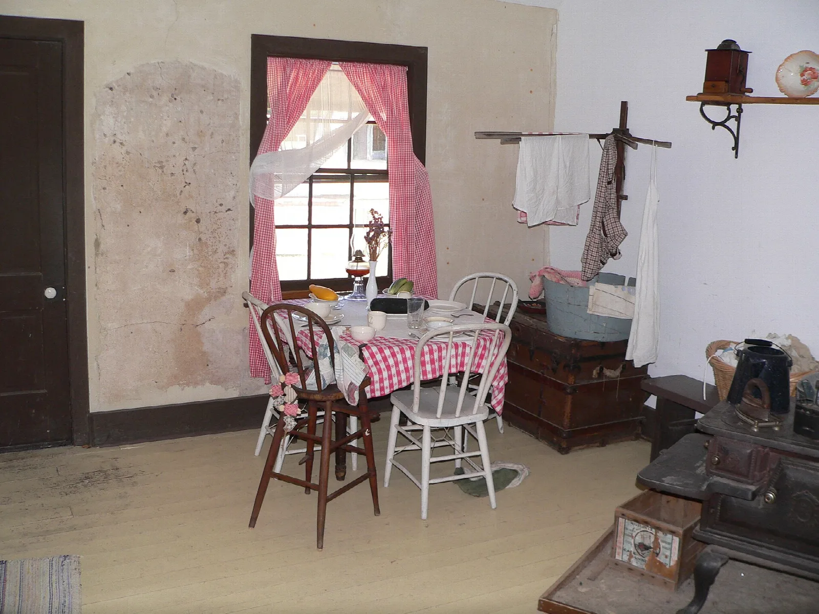 Historic room with a checkered table, chairs and a window with pink curtains