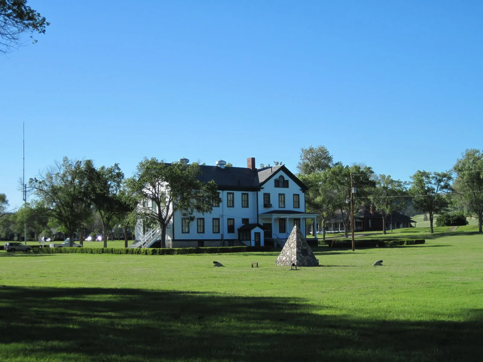 White museum building across a wide green lawn with trees behind it