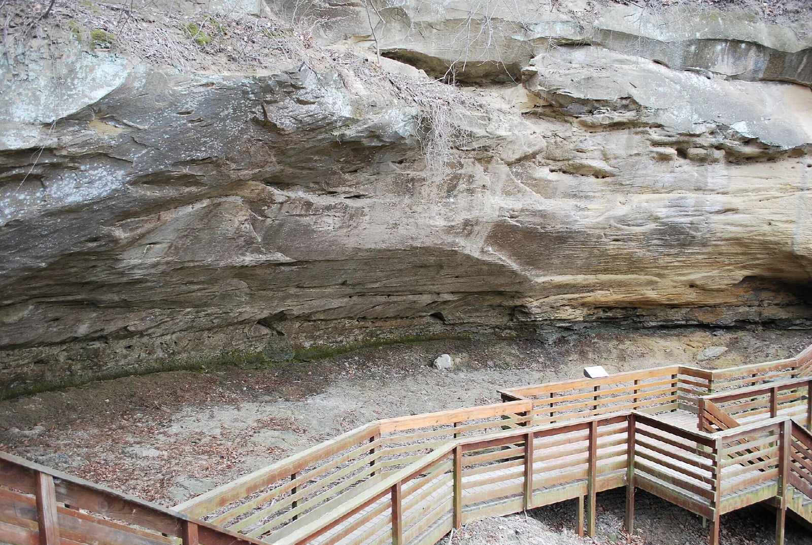 Wooden boardwalk and railing beneath a sandstone overhang